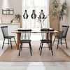 Four black Windsor dining chairs around a light wood table in a bright room.