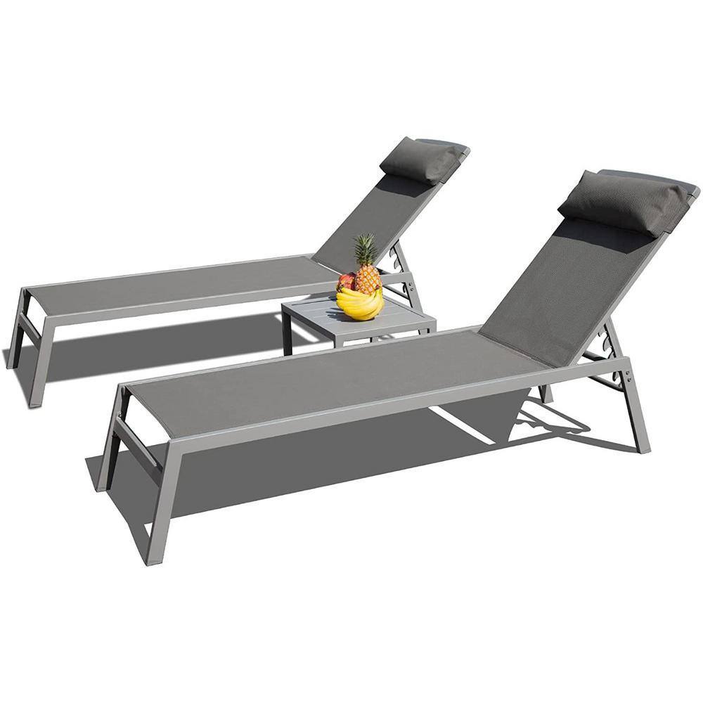 Two grey aluminum patio chaise lounges with headrest pillows and a side table with a pineapple on it.