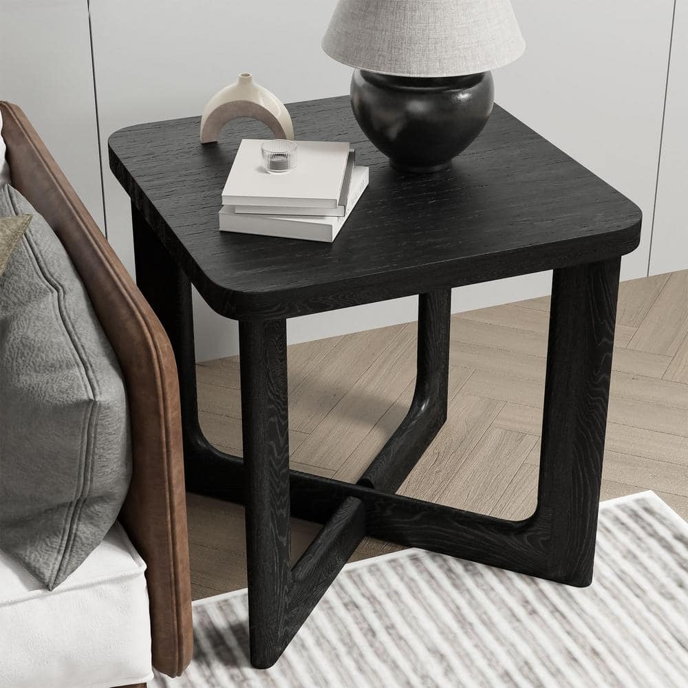 Black square wood end table with a lamp on a sofa.