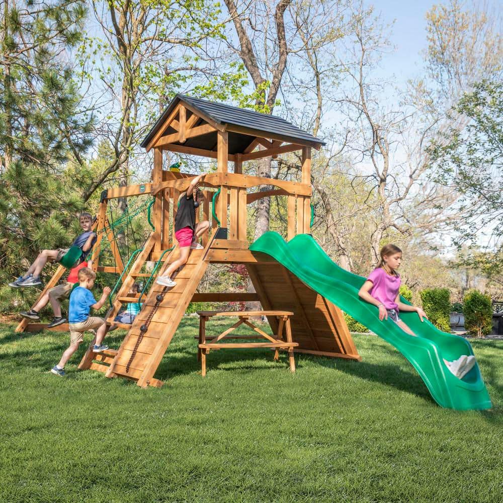 Backyard Discovery Endeavor II Outdoor Playground Set w/ Elevated Clubhouse, Climbing Wall, Swing Set, Green Wave Slide, and Picnic Bench