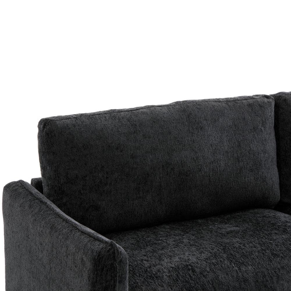 Close-up of the back cushion and armrest of a black chenille sofa.