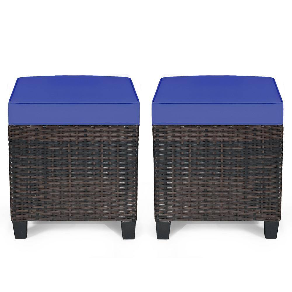 Two square outdoor wicker ottomans with navy blue cushions.