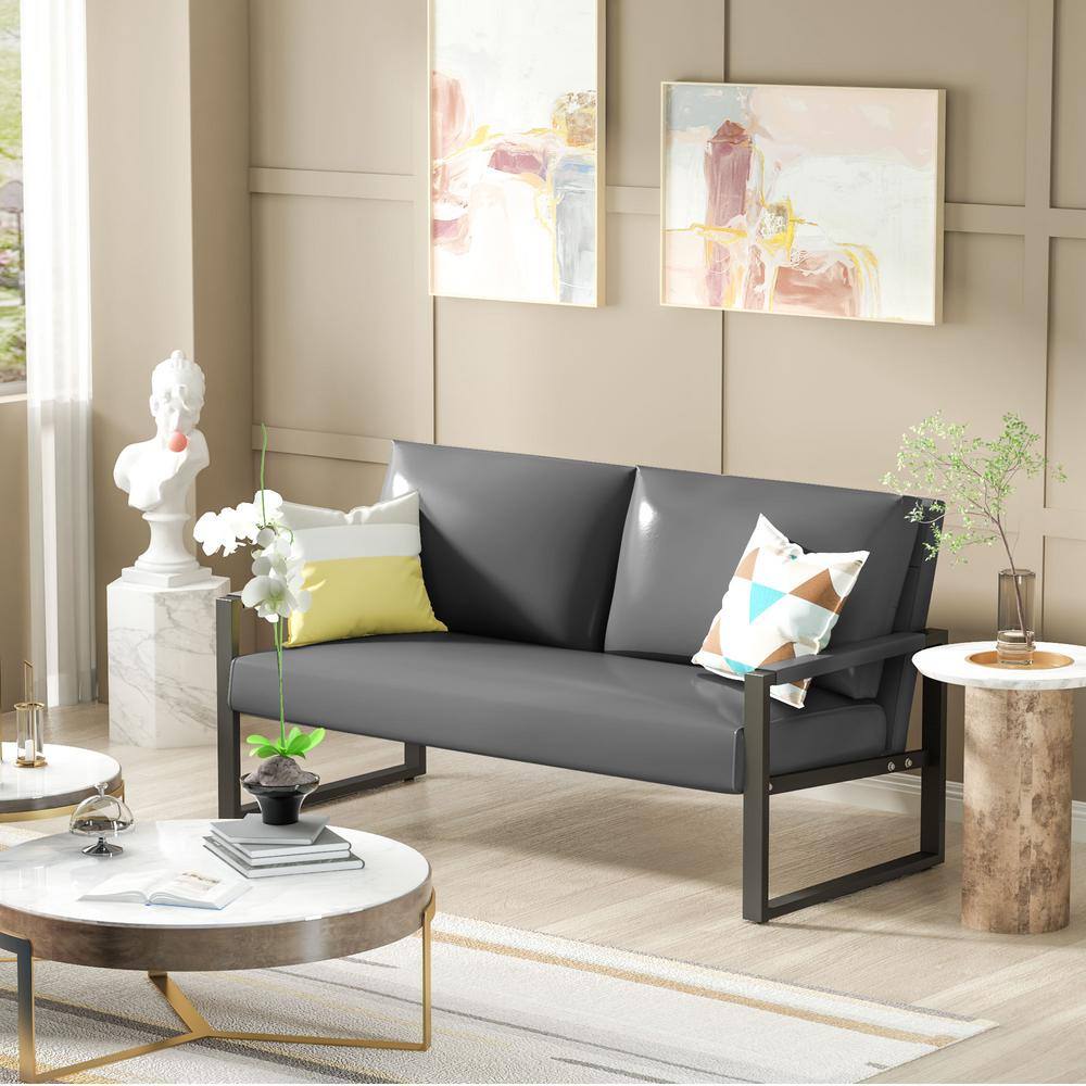 Gray faux leather loveseat with decorative pillows in a styled room.
