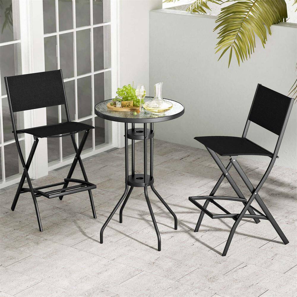 Two black folding metal bar stools and a small round bistro table set outdoors.