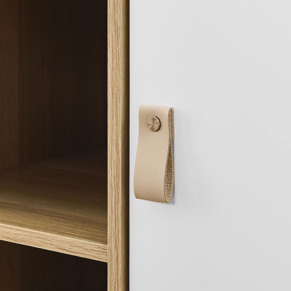 Close-up of the tan leather pull handle on the white cabinet door.