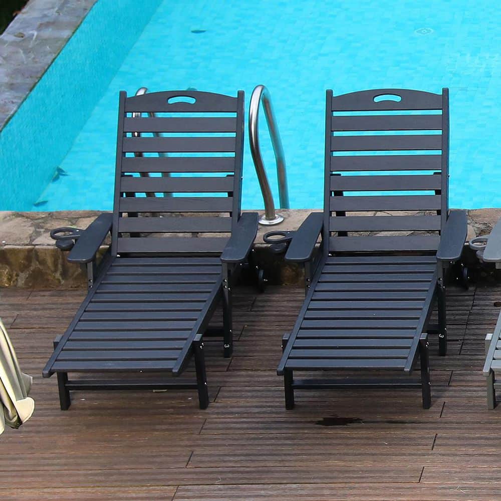 Two black chaise lounges by a pool.