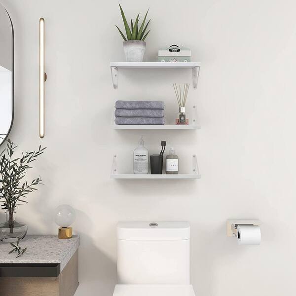 White modular shelves are mounted beside a drop-in bathtub fitted with  white horizontal surround tiles…