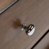 Close-up of a silver circular knob on a walnut dresser drawer.
