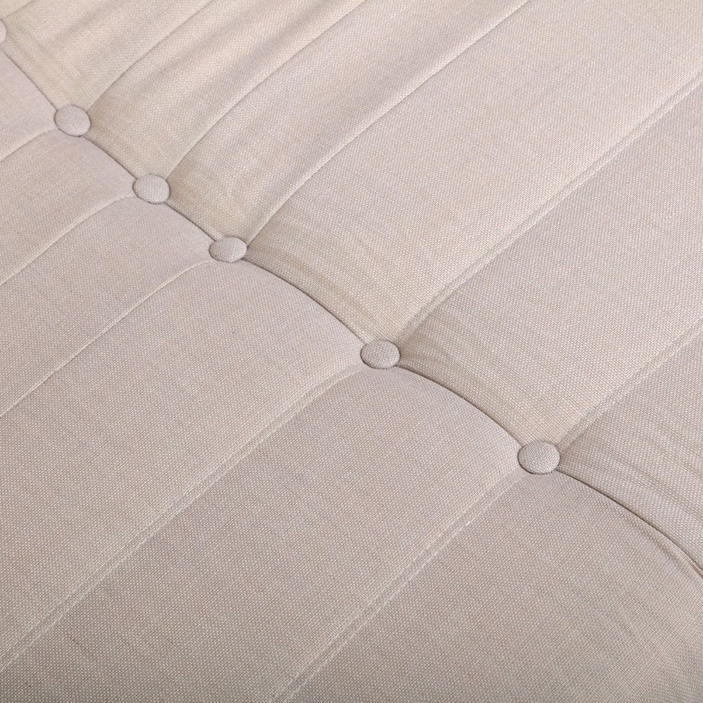 Close-up of the tufted buttons and stitching on beige furniture.