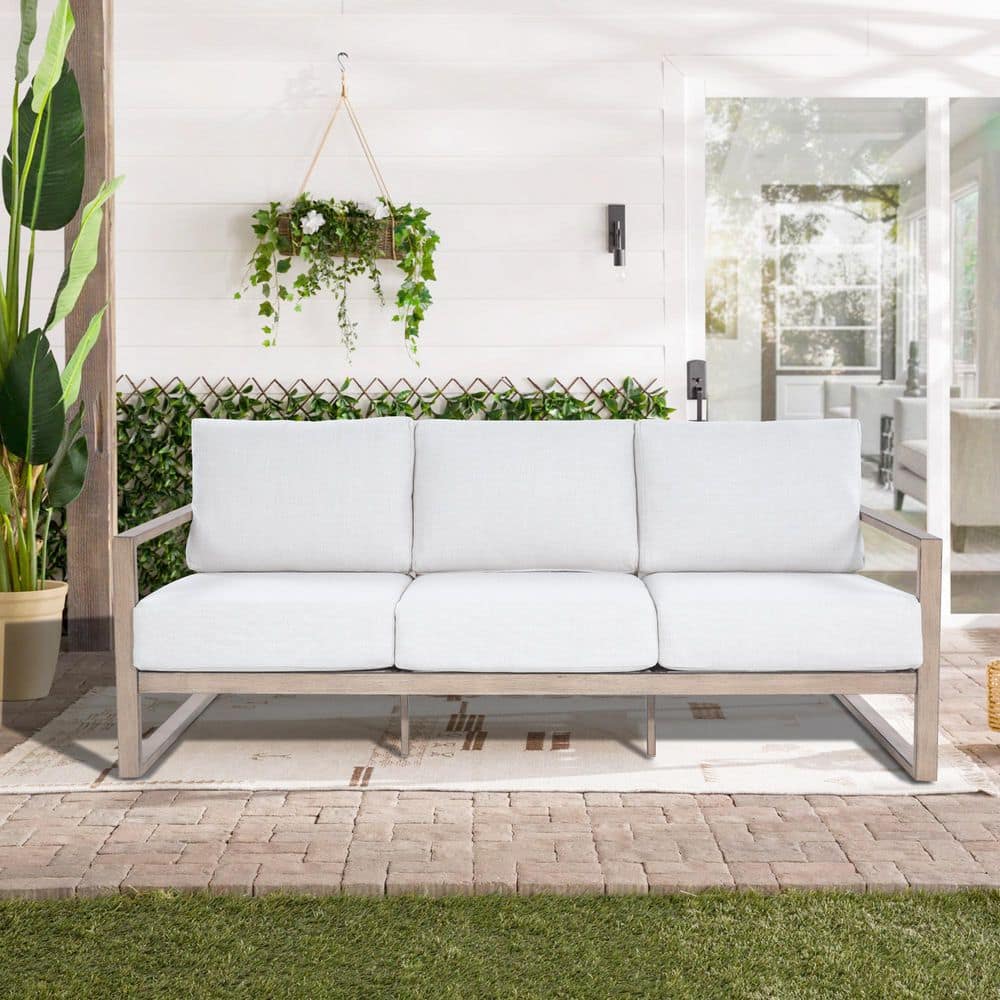 Hamarto aluminum outdoor sofa with white cushions against a white wall.