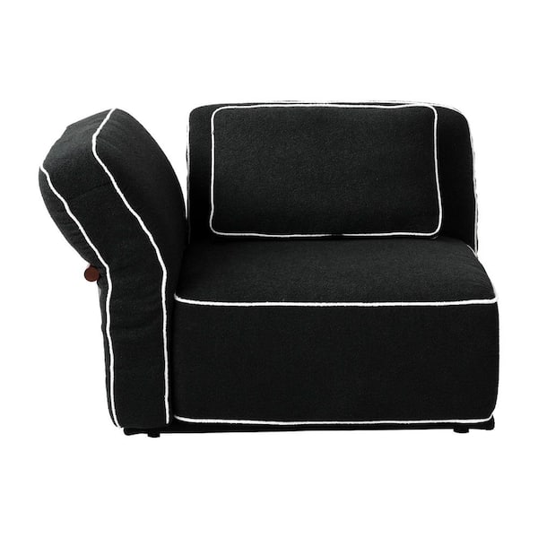 Black sofa with white piping, shown from a profile angle.
