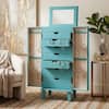 Open turquoise jewelry armoire in a styled bedroom.