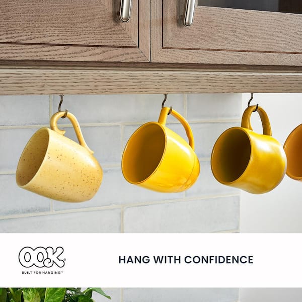 Coffee Cups Hanging On Hooks In Front Of Brick Wall Stock Photo