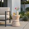 Outdoor side table in a modern patio setting with plants and a chair.