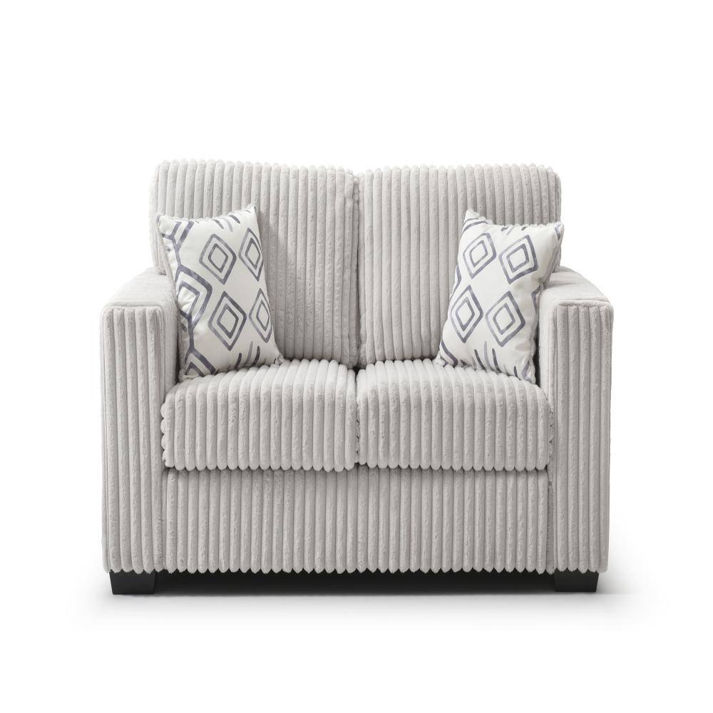 Ivory ribbed polyester loveseat sofa with two geometric patterned throw pillows.