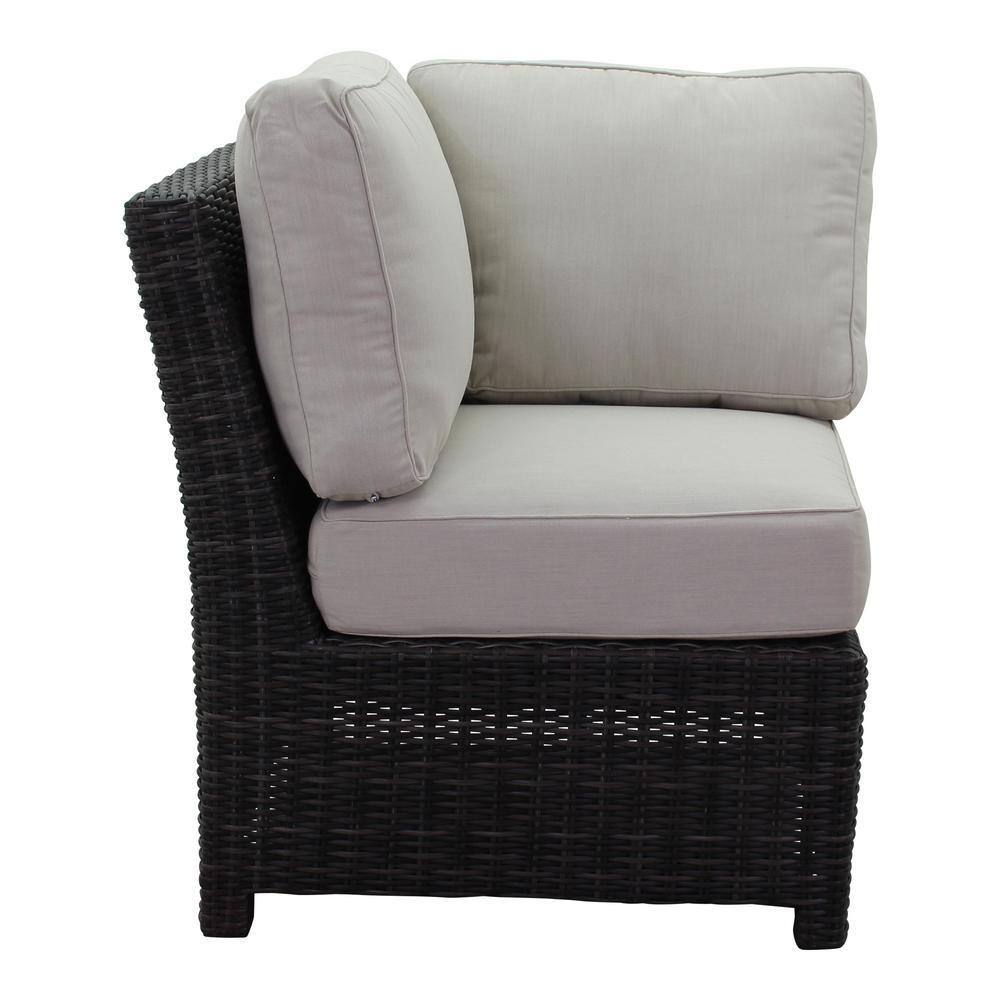 Corner piece of a dark brown wicker sectional with cream cushions.
