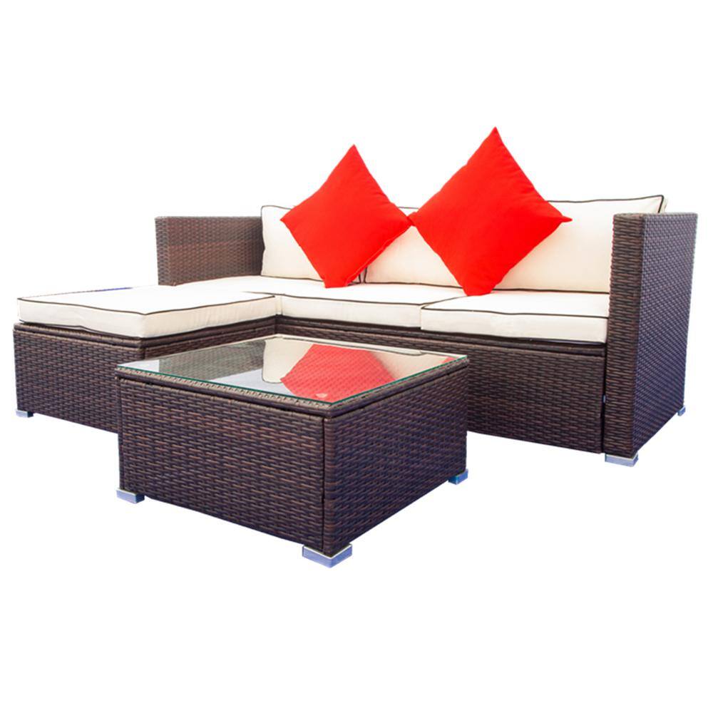 Black wicker 3-piece patio furniture set with beige cushions and red pillows, including a sectional sofa, stool, and glass-top table.