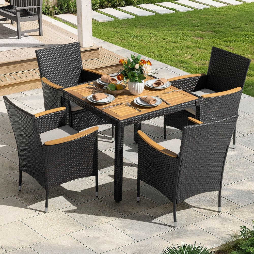 Set of four black wicker dining chairs around a wooden outdoor table.