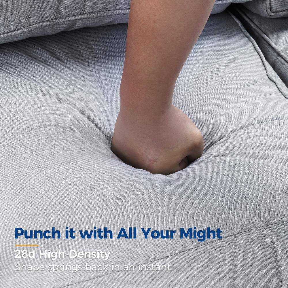 A hand pressing into a thick light gray cushion.