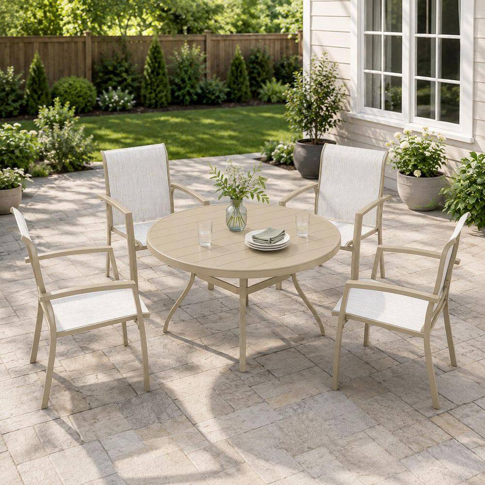 Light beige 5-piece outdoor dining set with a round table and four chairs on a stone patio.