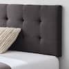Charcoal upholstered headboard with a textured throw pillow on a bed.
