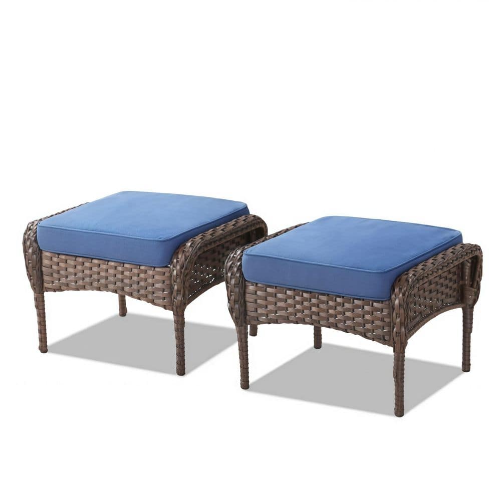 Set of two brown wicker ottomans with blue cushions.