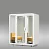 White office sound pod booth with two yellow chairs inside.