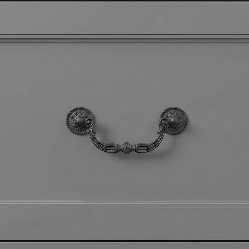 Close-up of a dark metal cup pull handle on a gray drawer.