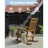Tan rocking chair on a wooden deck with plants.