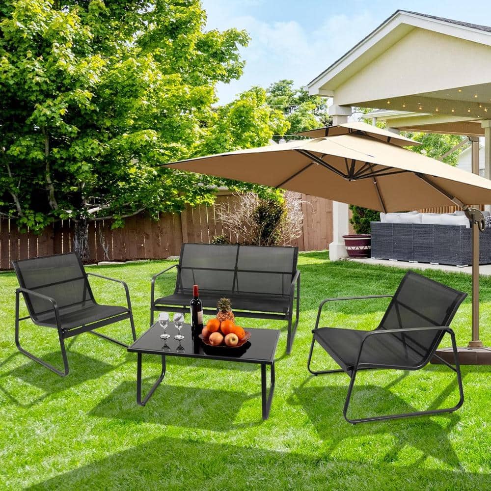 Black 4-piece outdoor chat set arranged on a green lawn under a patio umbrella.