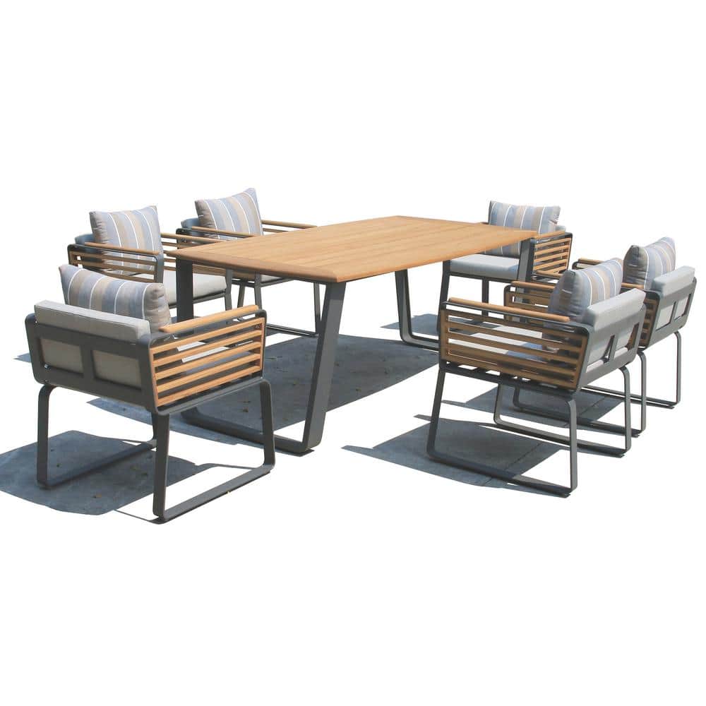 Outdoor dining set with wooden table and gray cushions on pavement.