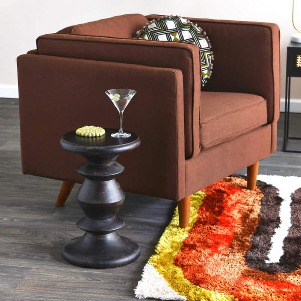 Brown armchair in a living room setting with a side table and rug.