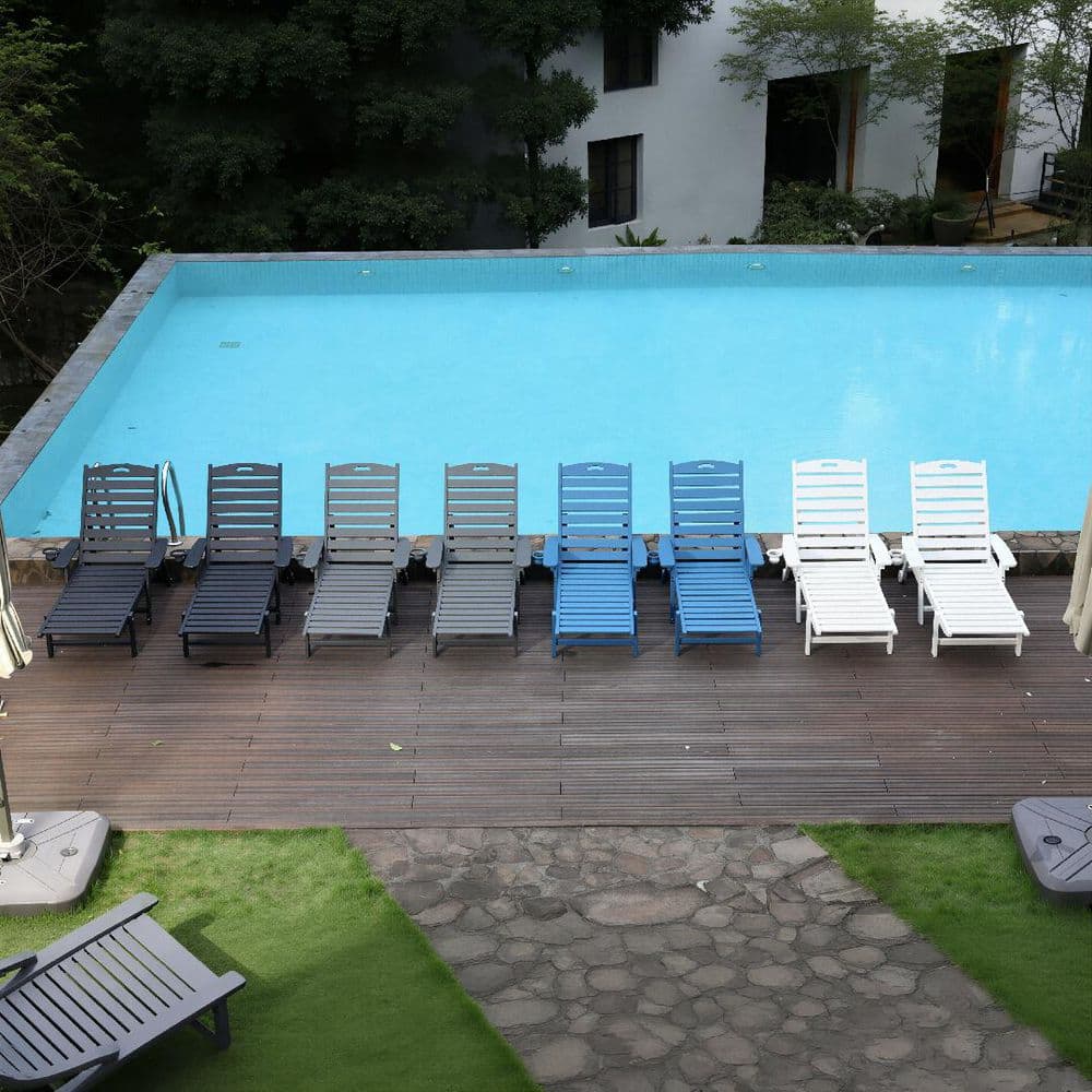 Group of black, blue, and white chaise lounges by a pool.