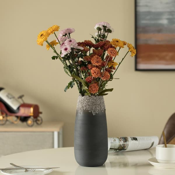 Dried wildflowers in grey clay or ceramic vase standing on table