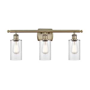 Clymer 26 in. 3-Light Antique Brass Vanity Light with Clear Glass Shade