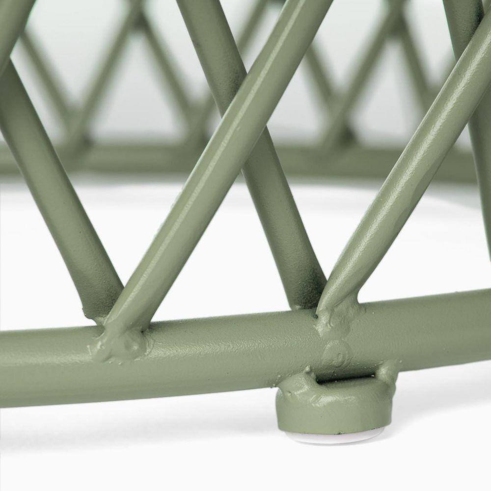 Close-up of the sage green metal lattice base of the side table.