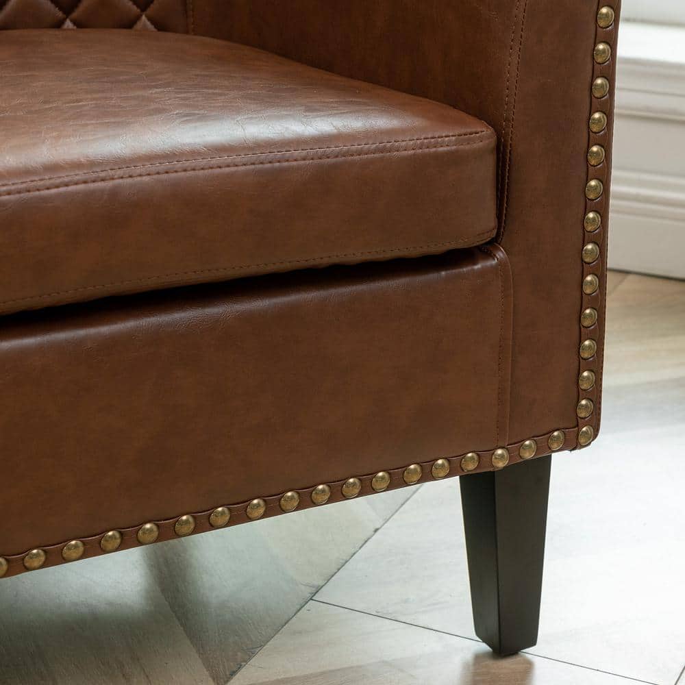 Detail of the nailhead trim and leg of a brown faux leather chair.
