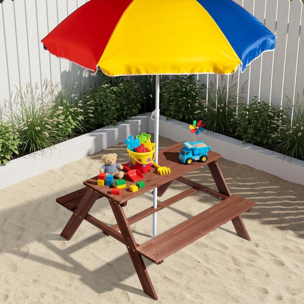Kids' brown wood picnic table with a colorful umbrella in a sandy outdoor setting.