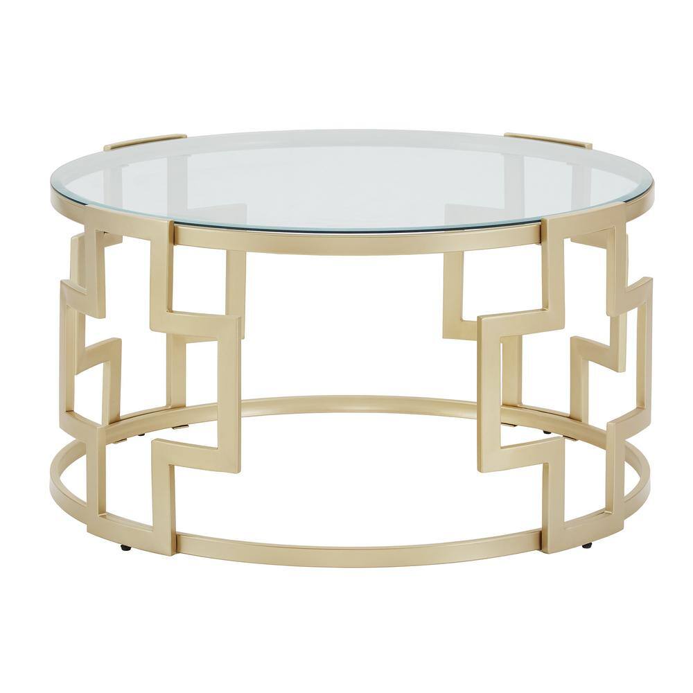 Round gold metal coffee table with a clear glass top, angled view.