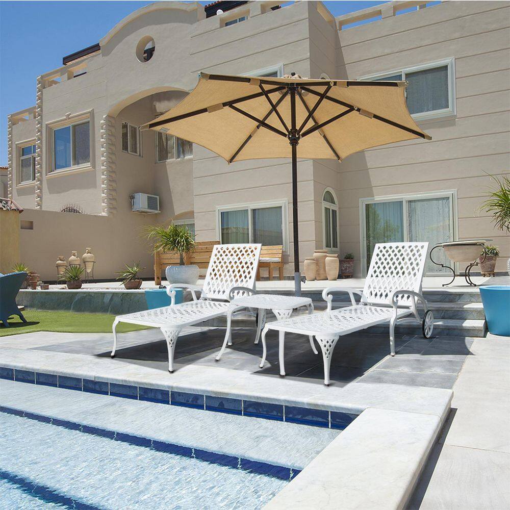Three white outdoor lounge chairs on a patio by a pool.