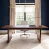 Brown wood desk in a modern home office with a desk lamp.