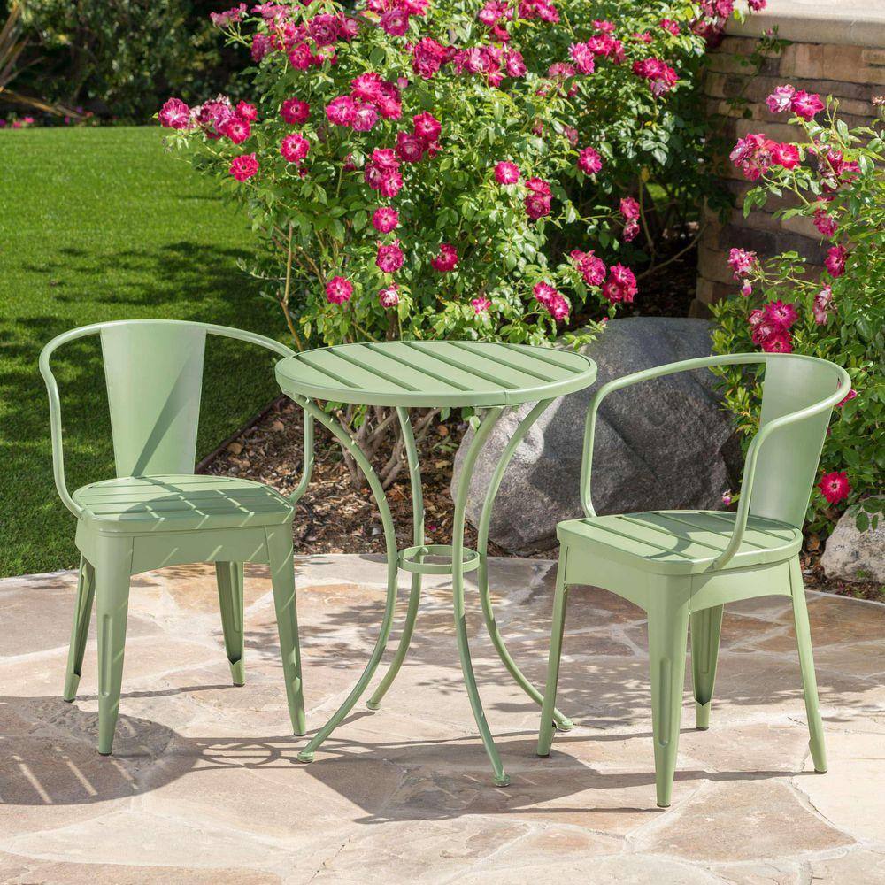 Complete green metal bistro set in a garden setting.