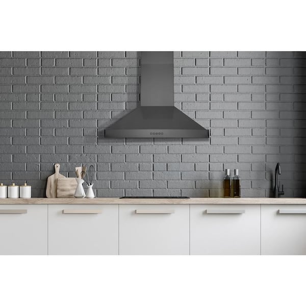 A black metal range hood is flanked by dark gray modern cabinets mounted in  front of windows.