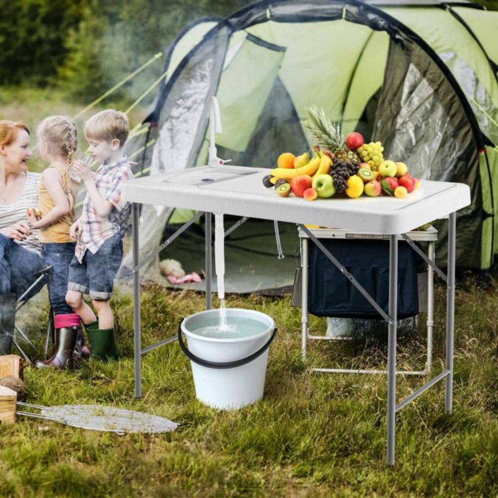 Folding table used outdoors at a picnic by a group of people.