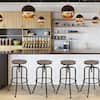 Four walnut wood grain backless bar stools with black metal frames lined up against a kitchen counter.