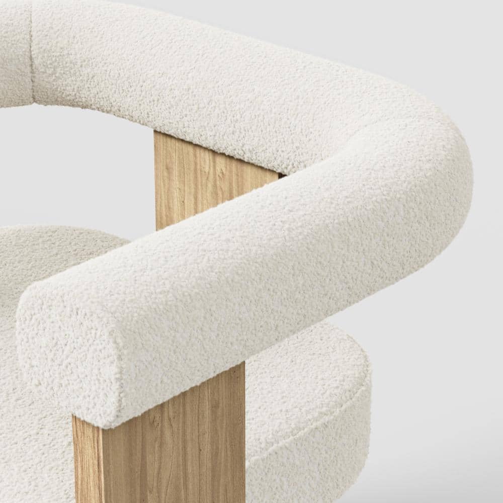Close-up of the cream bouclé upholstery on a chair armrest.