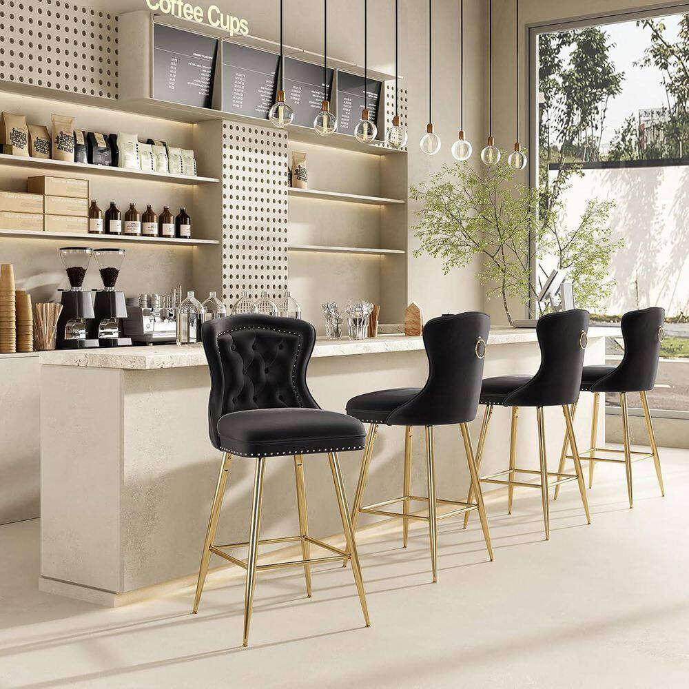 Four black velvet bar stools with gold legs arranged along a cafe counter.