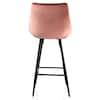 The back view of a pink velvet bar chair with black metal legs.
