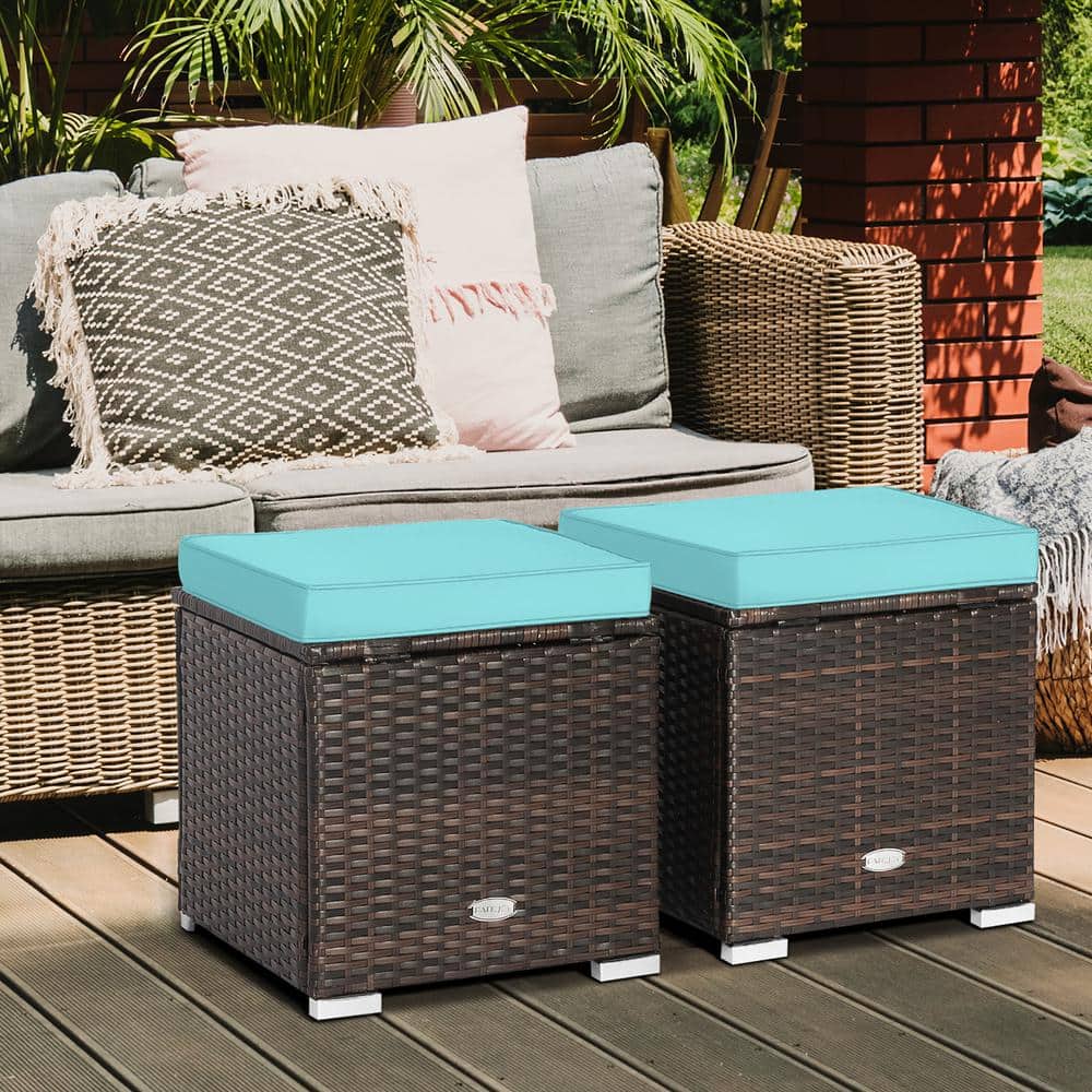 Two brown wicker outdoor patio ottomans with turquoise cushions placed next to a wicker sofa.