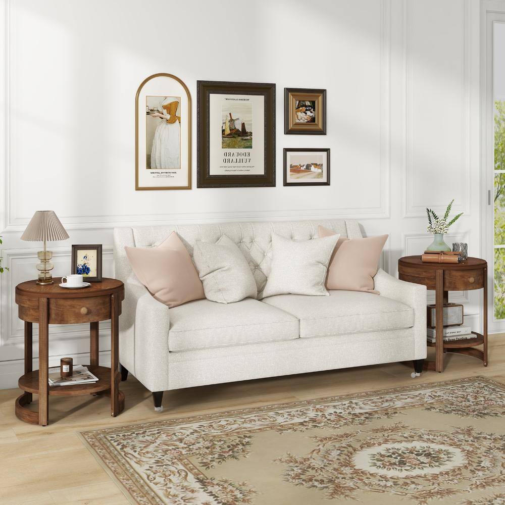 A living room scene with a white sofa and two round wooden end tables.